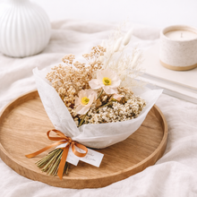 Load image into Gallery viewer, Bouquet of flowers wrapped in white paper with an orange ribbon on a wooden tray.