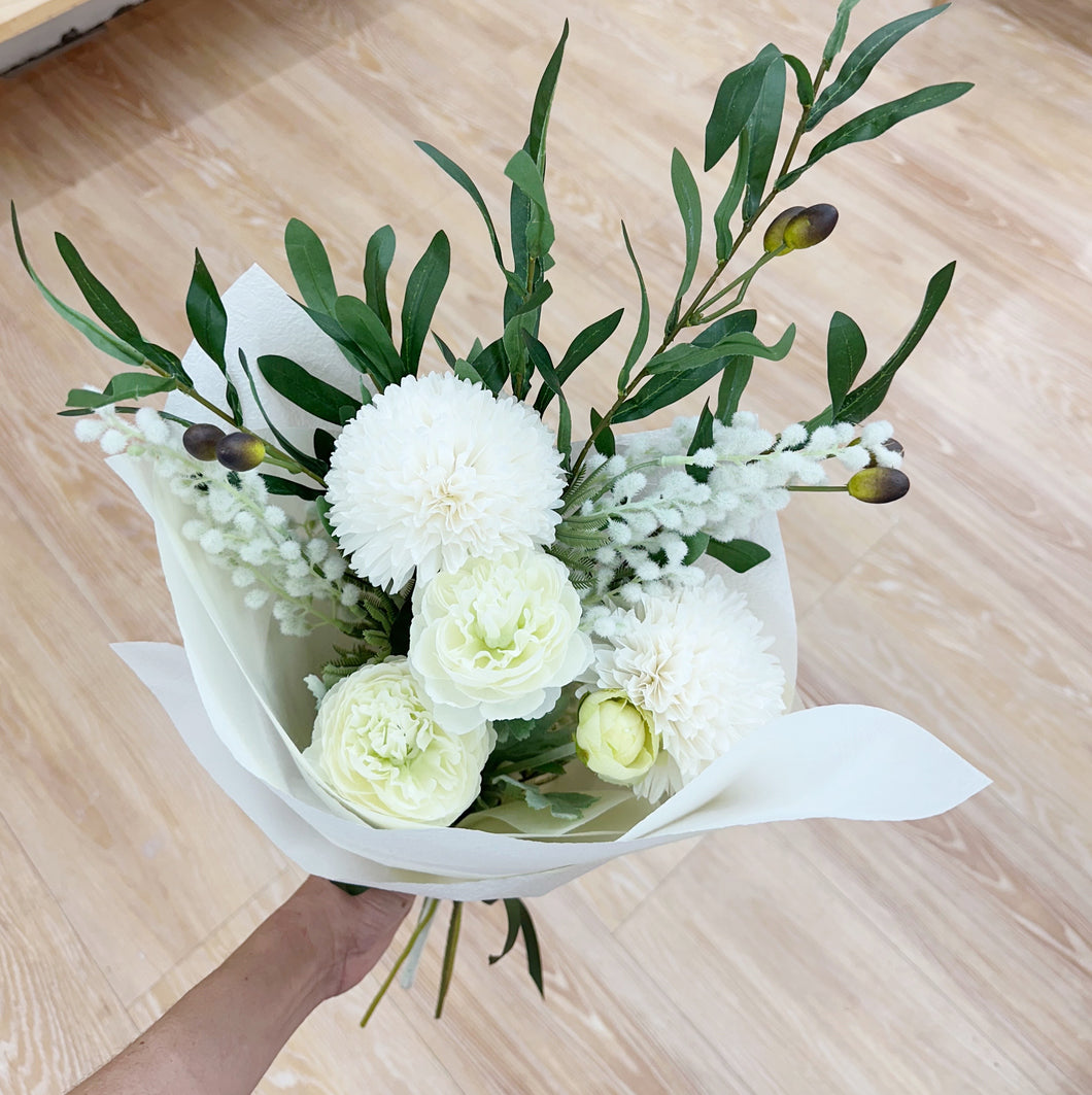 Bouquet of white flowers with green leaves on a wooden surface